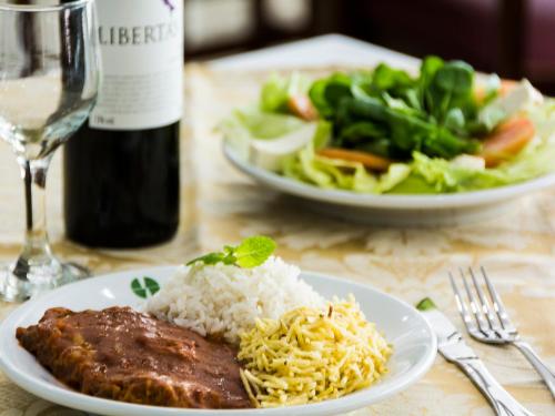 a table with a plate of meat and rice and a salad at Hotel Golden Park Sorocaba & Convenções by Nacional Inn in Sorocaba