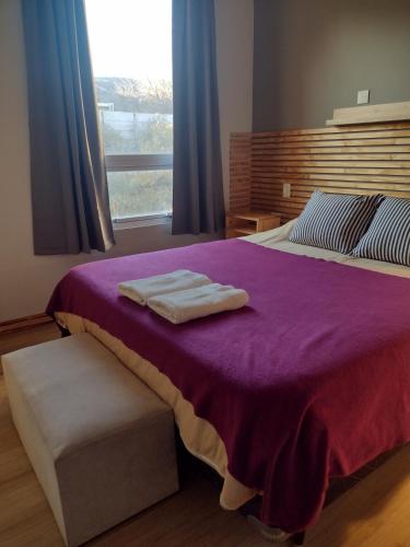 a bedroom with a purple bed with two towels on it at Complejo Phira in Puerto Pirámides