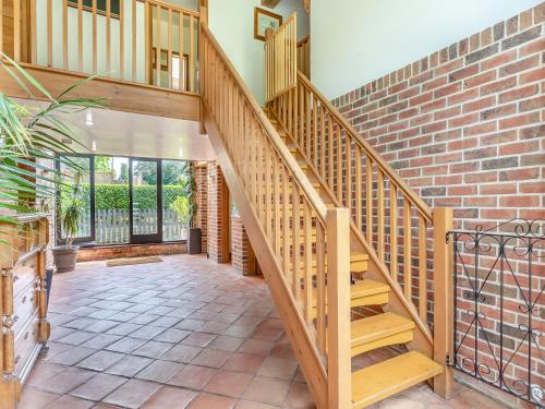 a staircase in a house with a brick wall at Clamp Farm Barn in Stowmarket