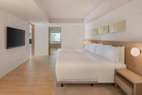 a bedroom with a white bed and a flat screen tv at IRAPH SUI, a Luxury Collection Hotel, Miyako Okinawa in Miyako Island