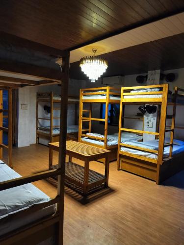 a room with three bunk beds with a table and a chandelier at Moondance Hostel & Garden Restaurant in Pushkar