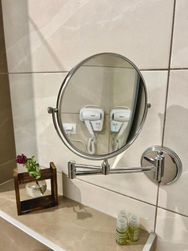 a round mirror on a bathroom wall with a phone at Vila Pozitiv in Sisevac