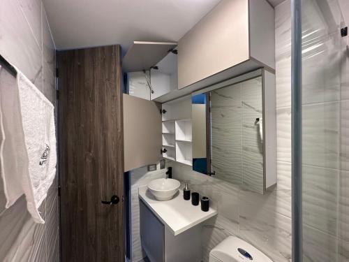 a bathroom with a sink and a toilet and a mirror at Apartaestudio moderno en el centro de la ciudad in Manizales