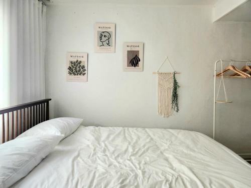 een wit bed in een slaapkamer met foto's aan de muur bij Bandal Stay in Daegu in Daegu