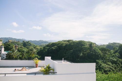 a woman laying on the roof of a house with trees at Florence Sayulita in Sayulita