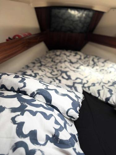 a bed with a black and white comforter and a pillow at Veludstyret båd, med indbygget varme og gratis Wifi in Fåborg