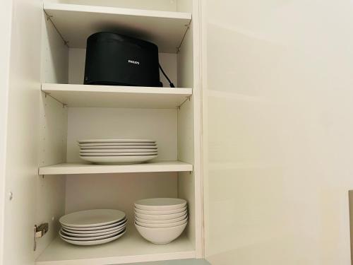 a cupboard with plates and bowls and a black appliance at APSTAY City Center I FREE Parking I Self Check-in in Graz