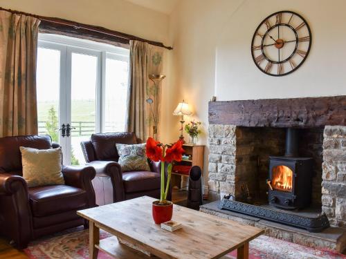 a living room with a fireplace and a table at High Dalton Hall Cottage in Newsham