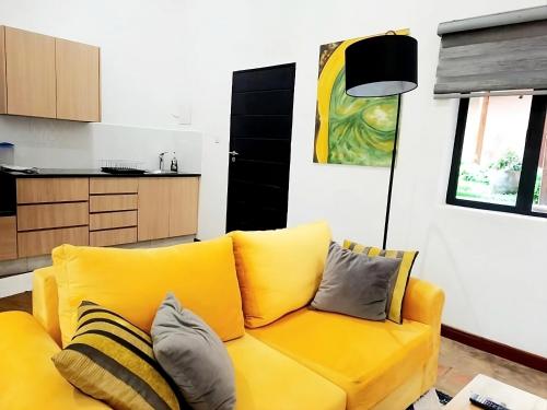a yellow couch in a living room with a kitchen at Amaryllis Residences Mount Pleasant in Blantyre
