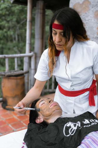 a woman brushing a persons face with a brush at Cabañas Los Achicuales in Cuetzalán del Progreso