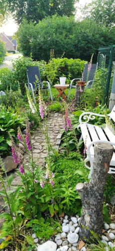 a garden with two white benches and flowers at Steinaublick Ferienwohnung - Schnell in Hamburg-Lübeck-Lüneburg-Schwerin-Ostsee in Büchen