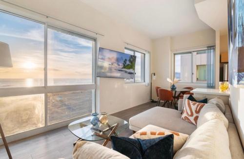 a living room with a couch and a large window at The Sunstone - Full Oceanview Right On The Sand in Los Angeles