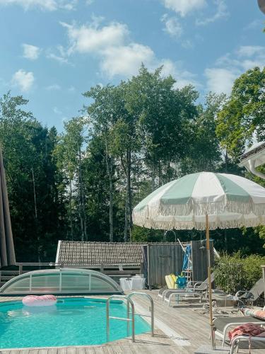 a swimming pool with an umbrella and a table and chairs at Charming 1900S Cottage In Billinge Village in Norrtälje