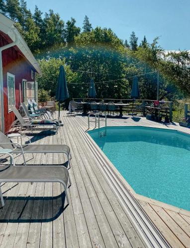 a swimming pool on a wooden deck with chairs and umbrellas at Charming 1900S Cottage In Billinge Village in Norrtälje
