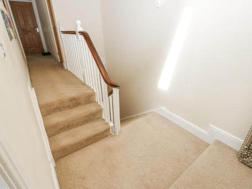 a hallway with a staircase with white walls and carpet at St Ronans in Bishop Auckland