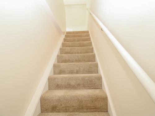 a staircase with brown carpet and white walls at St Ronans in Bishop Auckland