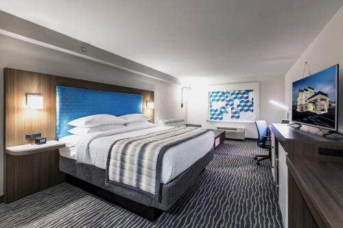 a hotel room with a bed and a flat screen tv at Wingate Augusta Washington Road by Wyndham in Augusta