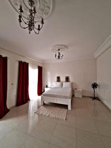 a bedroom with a bed with red curtains and a chandelier at Private Room in Luxury Villa Secure Gated Area, Dakar in Pikine