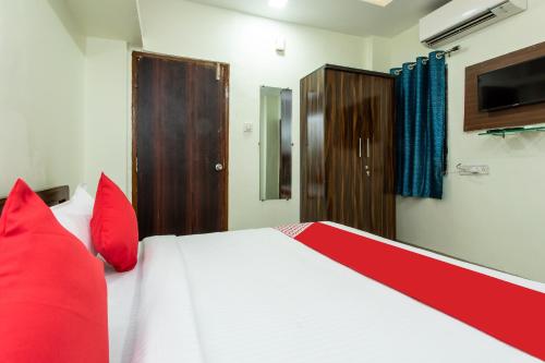 a bedroom with a large bed with red pillows at Hotel O Manjulam Regency in Indore