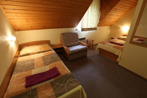 a bedroom with two beds and a chair in a room at Penzión Čachovo in Selce