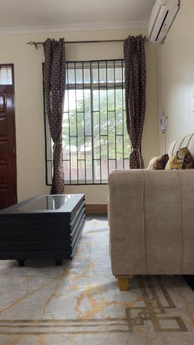 a living room with a couch and a large window at Grace Haven Airport Day-Use & Overnight Stays Hotel in Dar es Salaam