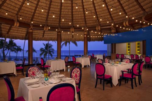 a restaurant with tables and chairs with the ocean in the background at Altitude by Krystal Grand Los Cabos - All Inclusive in San José del Cabo