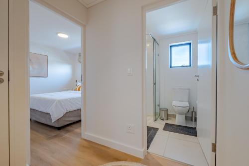 a bedroom with a bed and a glass door leading to a bathroom at Chic Coastal Hideaway in Hermanus