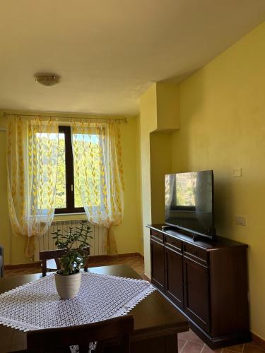 a living room with a table and a flat screen tv at Casale dei Gelsomini - Country House in Poggio