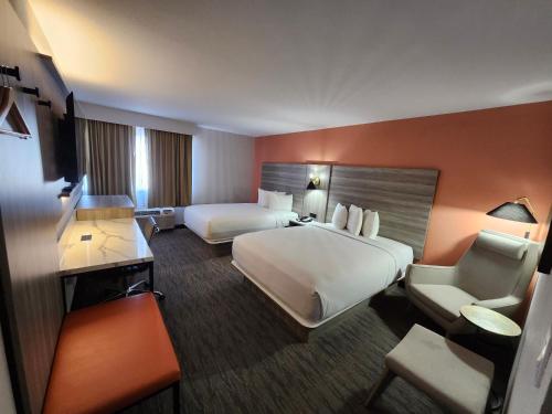 a large hotel room with two beds and a chair at The Grand Inn Peoria in Peoria