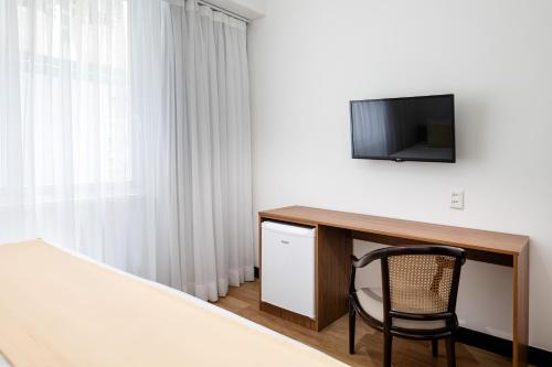 a bedroom with a desk with a television and a chair at Savoy Othon Lite in Rio de Janeiro