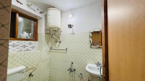 a bathroom with a sink and a toilet and a mirror at Hotel Indra in Srinagar
