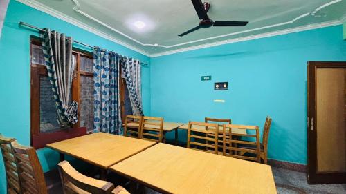 a dining room with blue walls and wooden tables and chairs at Hotel Indra in Srinagar