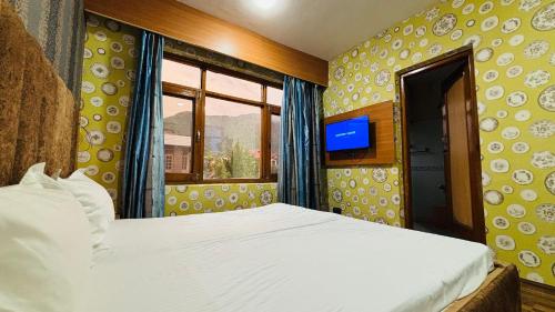 a bedroom with a bed and a window and a television at Hotel Indra in Srinagar