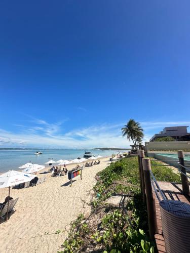a beach with chairs and umbrellas and the ocean at Barra Bali Resort in Barra de São Miguel
