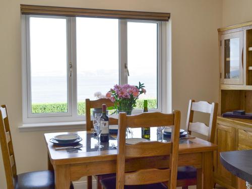 a dining room with a table and chairs and windows at Eilean View Island View in Midtown Brae