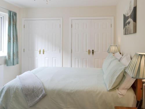 a bedroom with a white bed with two white doors at Eilean View Island View in Midtown Brae