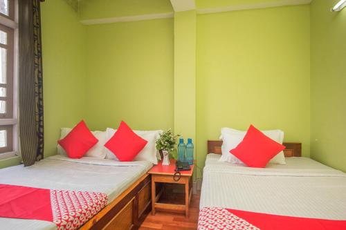 two beds in a room with red and white pillows at Hotel O Demadzong in Gangtok