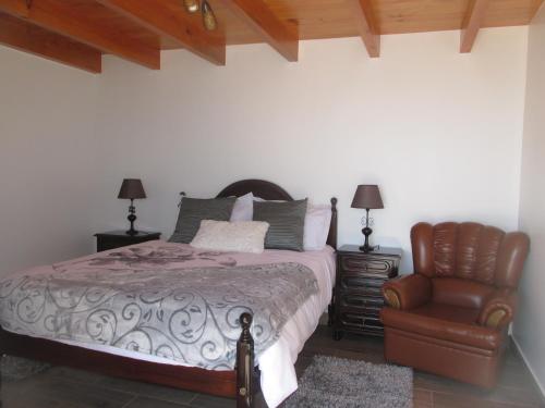 a bedroom with a bed and a chair at Casa Formiga in Fajã da Ovelha