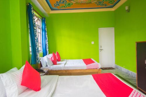 a green room with two beds with red pillows at Hotel O Demadzong in Gangtok