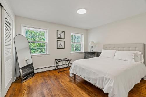 a white bedroom with a bed and a mirror at New Pristine Suburban Escape in Newtown Square