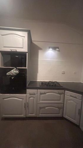 a kitchen with white cabinets and a black counter top at Appart équipé tout confort in Le François