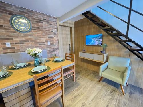 a dining room with a table and a clock on a brick wall at Casa em Penha- SC in Penha