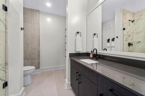 a bathroom with a sink and a toilet and a mirror at Modern Channelside 1BD Apartment | Close to DT! in Tampa