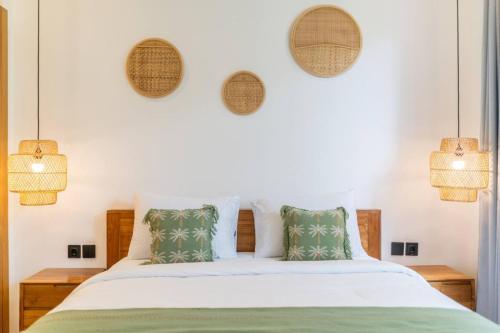 a bedroom with a bed with white sheets and green pillows at Amal Villa #10 by Bali Bliss Properties in Mengwi
