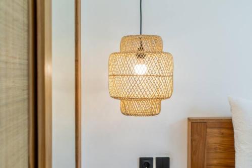 a rattan light fixture hanging from a wall at Amal Villa #10 by Bali Bliss Properties in Mengwi