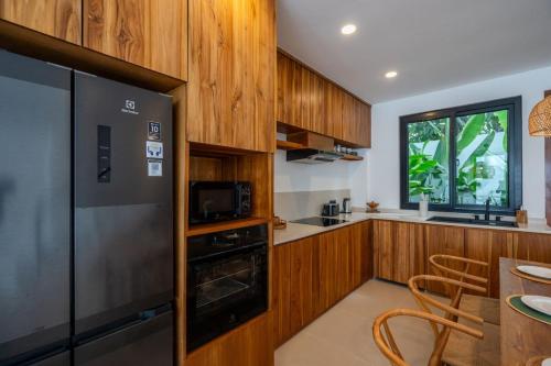 a kitchen with wooden cabinets and a stainless steel refrigerator at Amal Villa #10 by Bali Bliss Properties in Mengwi