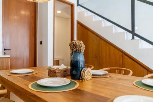 a wooden table with plates and a blue vase with flowers at Amal Villa #10 by Bali Bliss Properties in Mengwi