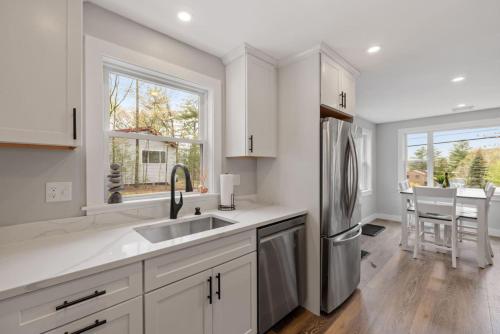 a kitchen with white cabinets and a stainless steel refrigerator at Central Location 4BR w Boat Slip Option in Gilford