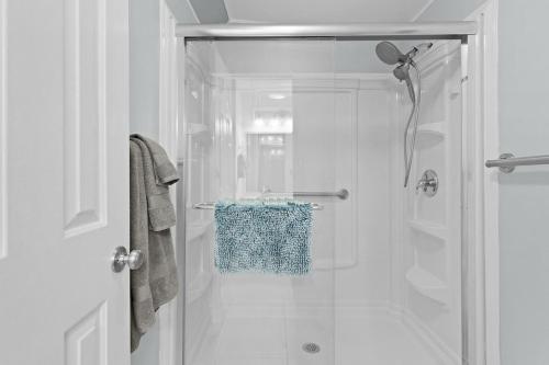 a white bathroom with a shower with a towel at Sunlit 2BR with Lanai on Golf Cart Path in Lady Lake