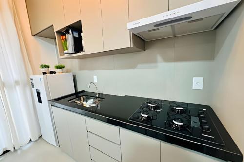 a kitchen with a black counter top and a refrigerator at *Loft Refúgio Urbano | Estilo e Conforto. in Uberlândia